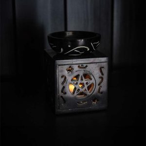 Brûleur de fondants parfumés fermé, orné d'un motif de pentacle avec une lueur douce provenant de l'intérieur.